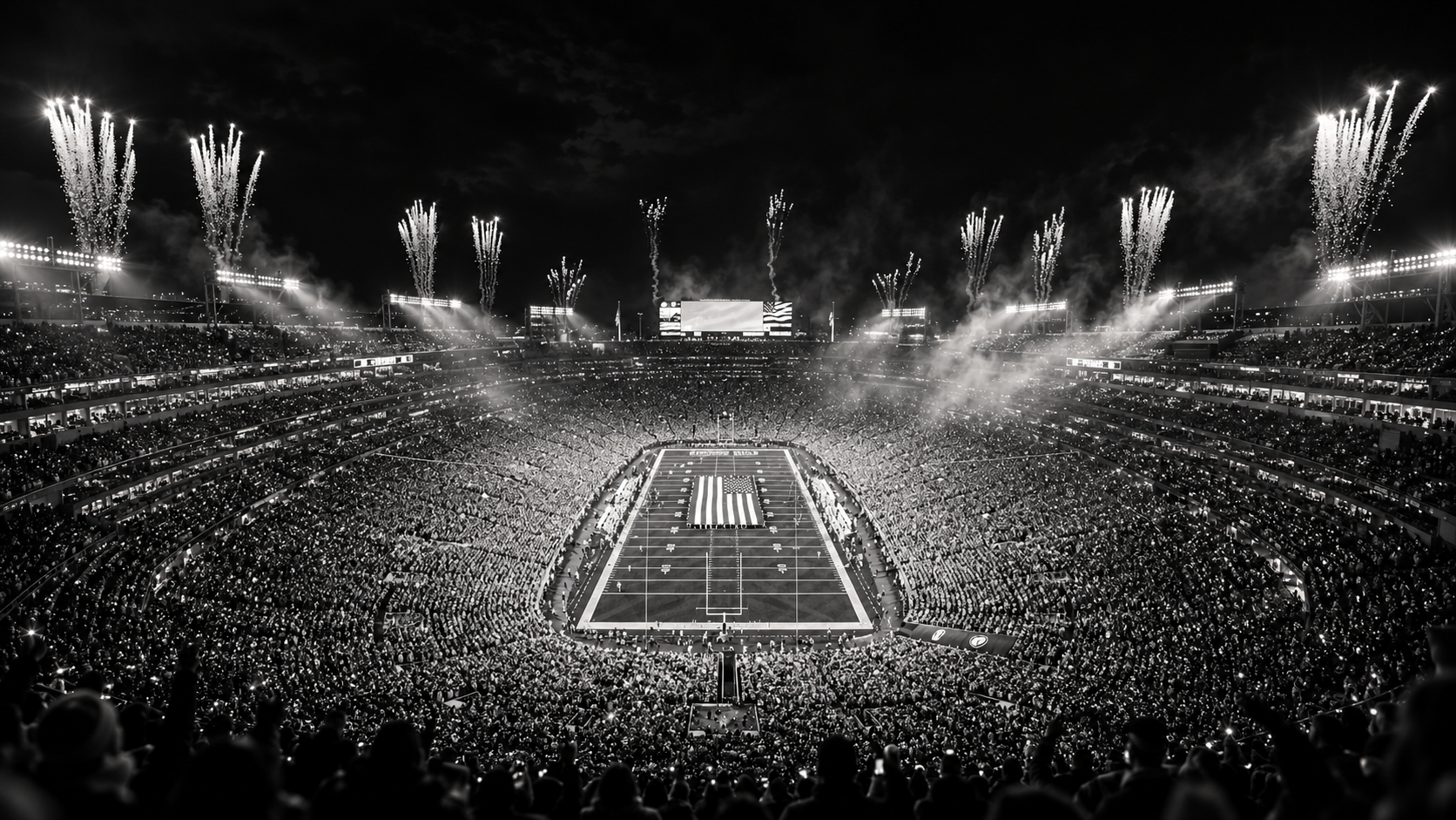 A vast stadium crowd surrounds the illuminated football field as fireworks rise into the night.